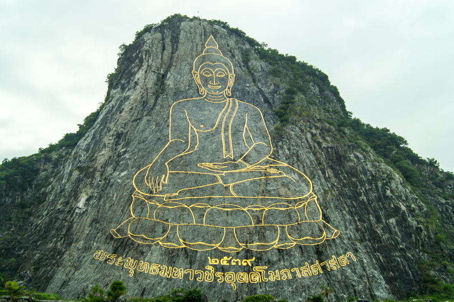Statua dorata del Buddha scolpita nella pietra della montagna