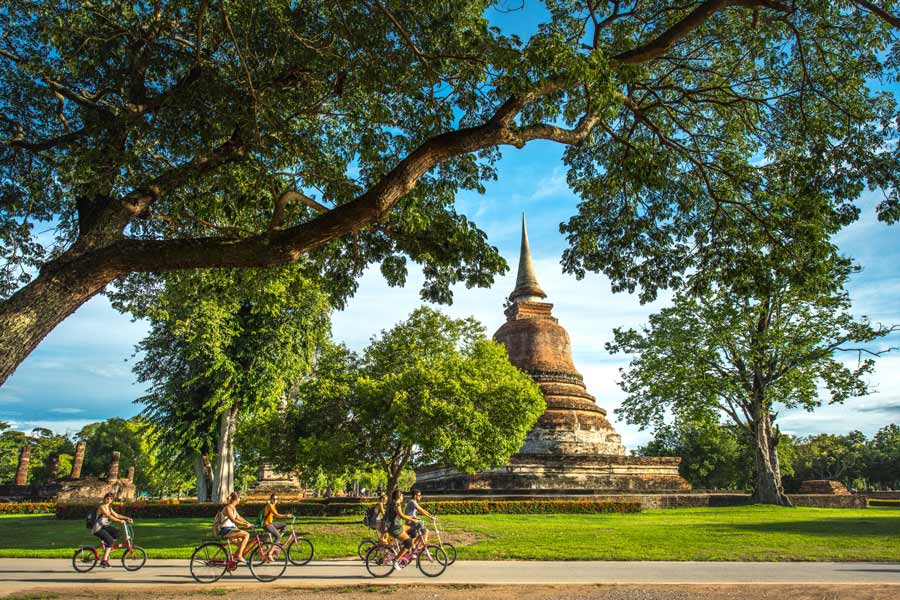 Turisti in bicicletta tra le antiche rovine di Sukhothai