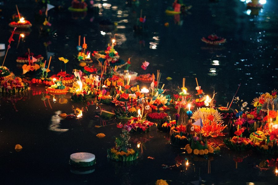Cestini fioriti galleggianti (krathong) illuminati che scorrono sullacqua durante il Loy Krathong