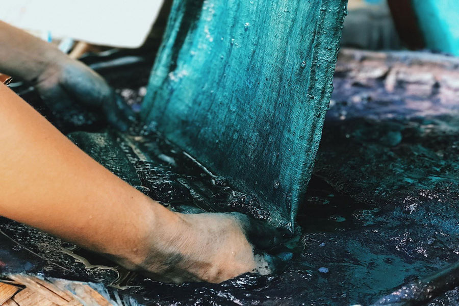 Mani che tingono fili di seta con colori naturali per il tessuto