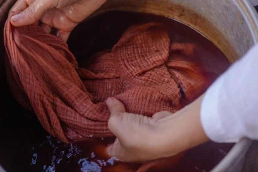 Un tessuto ikat laotiano di rosso in un bagno di colore naturale