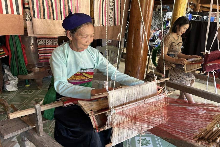 Un’antica tessitrice laotiana al lavoro con un telaio tradizionale 