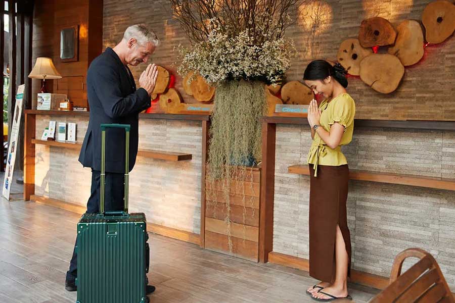 Stranieri e tailandesi eseguono rituali di saluto tradizionali
